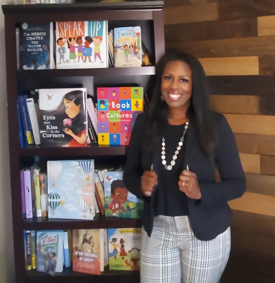 Jocelynn Hubbard in front of a bookshelf of diverse children's books