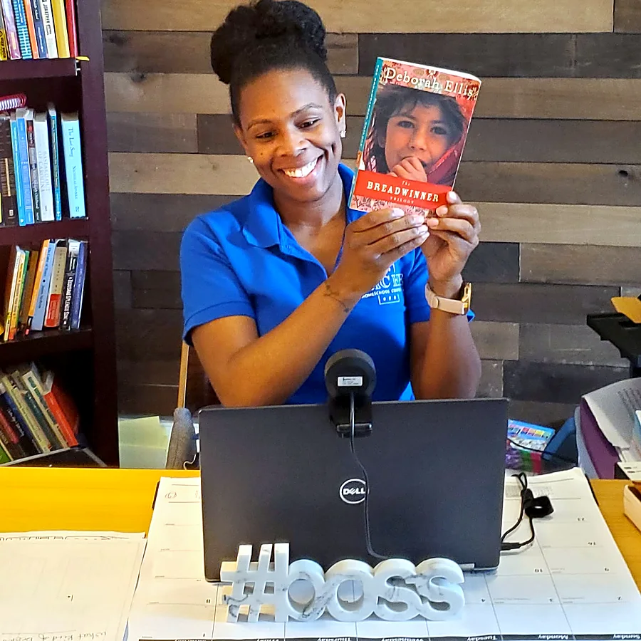 Jocelynn smiling and holding up a novel during a virtual session